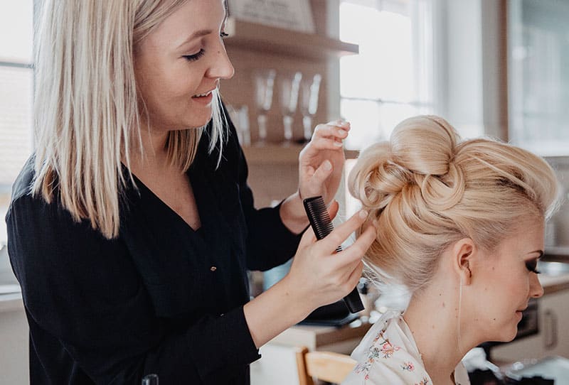 Mobile Hairstylistin steckt die Haare von Braut zu Hochsteckfrisur