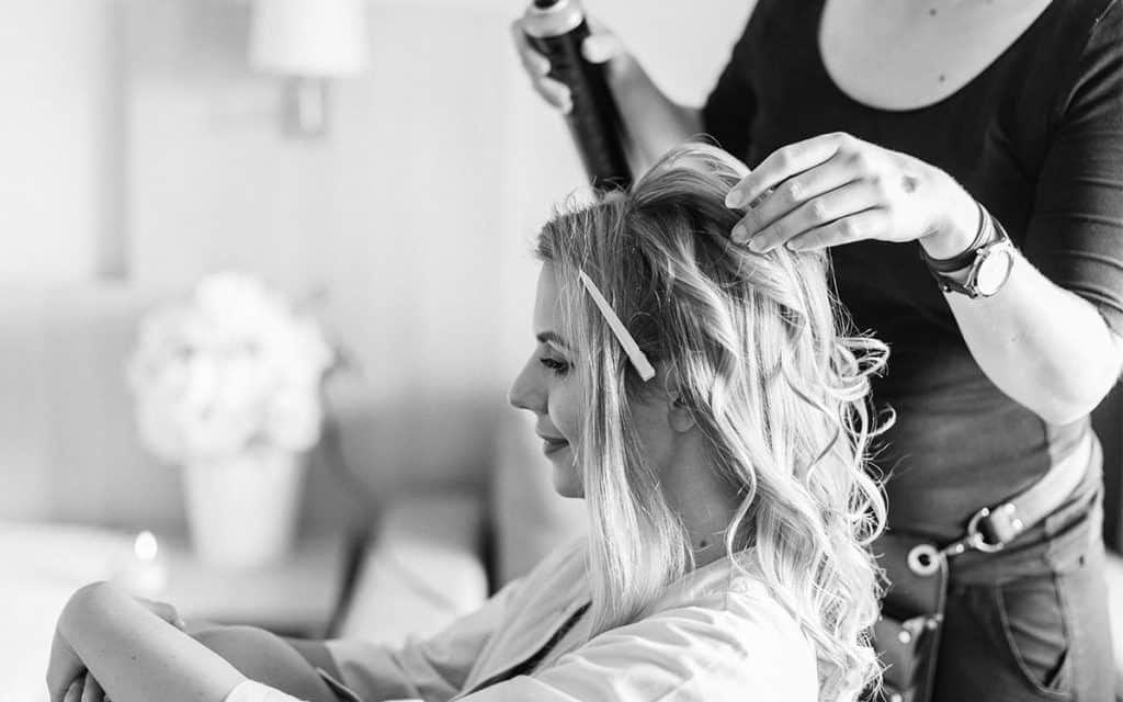 Brautstylistin macht entspannter Braut die Hochzeitsfrisur