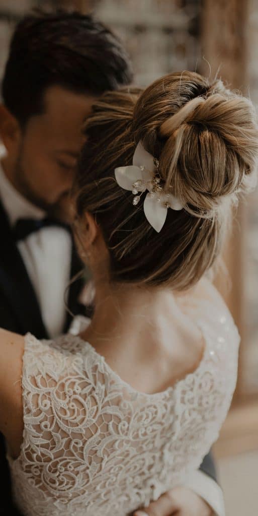Braut trägt romantische Hochzeitsfrisur mit Haarschmuck aus Lederblüten